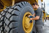 Une personne portant un équipement de sécurité utilise une clé à chocs sans fil sur une grosse roue de camion.