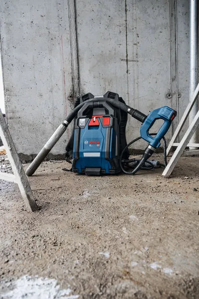 Aspirateur à dos sans fil posé sur le sol d'un chantier.