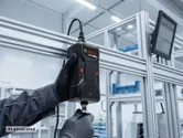 Une personne portant un équipement de sécurité connecte un appareil IPU-30 à une structure métallique dans une usine.