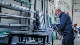 Une personne portant un équipement de sécurité meule une barre de métal, produisant des étincelles.