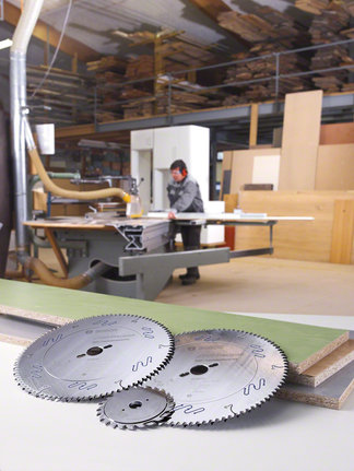 Un travailleur portant un équipement de sécurité utilise une scie circulaire dans un atelier de menuiserie.