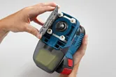 Una persona apre la piastra di base di un utensile elettrico portatile di colore blu.