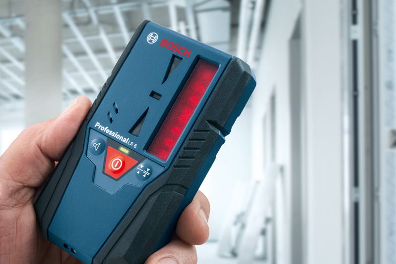 Persona che tiene in mano un ricevitore laser in un edificio in costruzione.