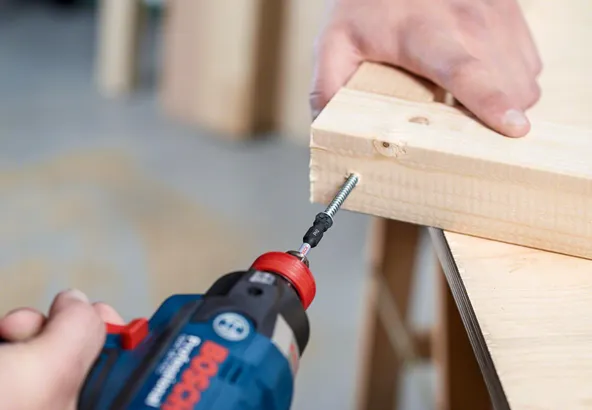 Trapano a batteria che avvita una vite in due pezzi di legno uniti.