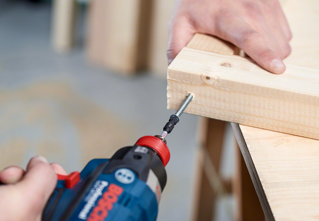 Trapano a batteria che avvita una vite in due pezzi di legno uniti.