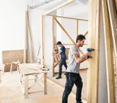 Due uomini costruiscono un muro di legno.