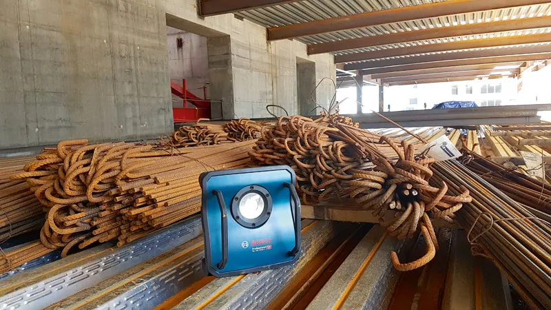 Pile di barre d'armatura con lampada da lavoro.