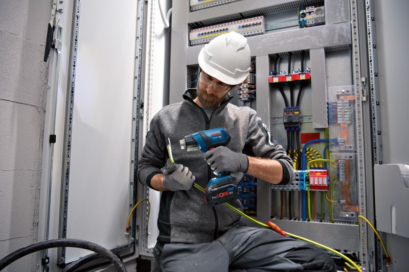 Una persona che indossa un equipaggiamento di sicurezza utilizza una pistola termica senza fili sui cavi elettrici.