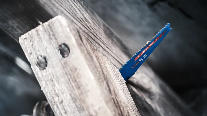 Lama di sega che taglia una spessa tavola di legno.