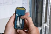 Persona che inserisce le batterie nel retro di un misuratore laser.