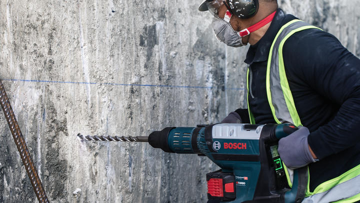 Una persona che indossa un equipaggiamento di sicurezza fora un muro di cemento.