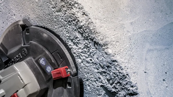 Levigatrice per calcestruzzo che leviga un muro intonacato grezzo.