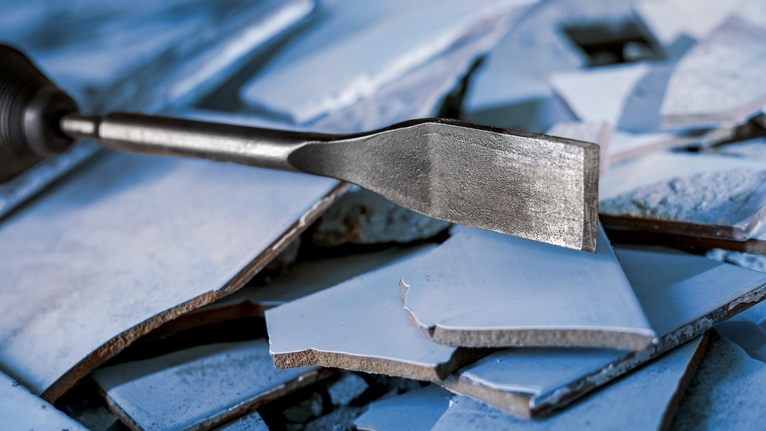 Scalpello per rimuovere piastrelle di ceramica rotte da un pavimento.