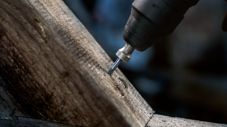 Utensile rotante che ricava una scanalatura in una trave di legno.