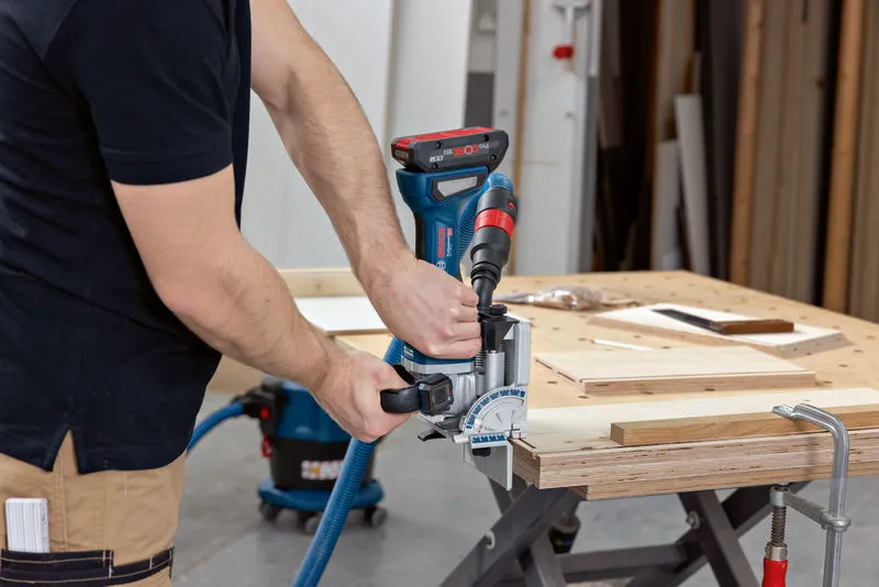 Una persona usa una giuntatrice per tagliare delle fessure nelle assi di legno su un banco da lavoro.