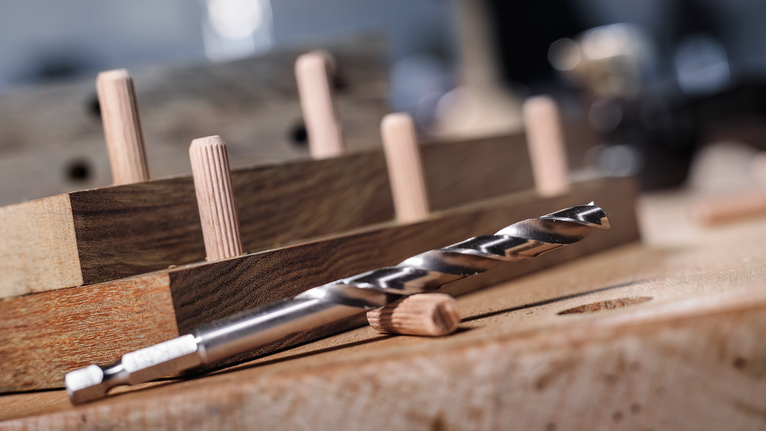 Punta da trapano e tasselli di legno posizionati su un banco da lavoro per la lavorazione del legno.
