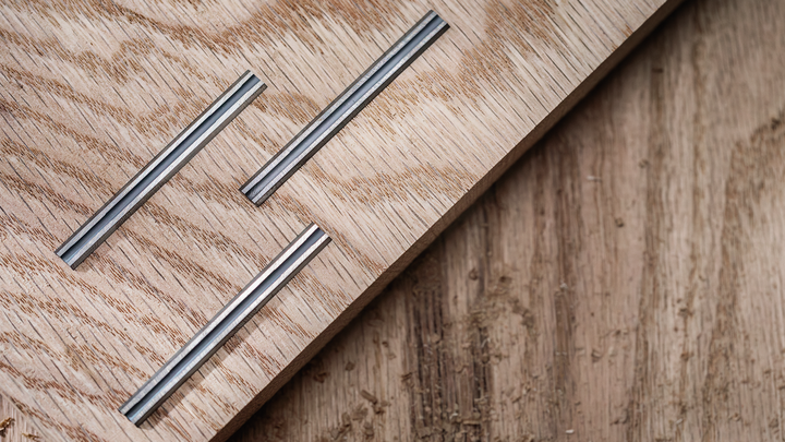 Tre intarsi metallici scanalati incastonati in una tavola di legno chiaro.