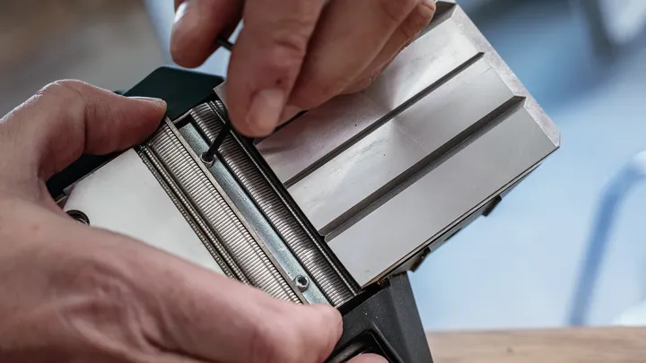 Una persona regola un componente di uno strumento metallico utilizzando una chiave esagonale.