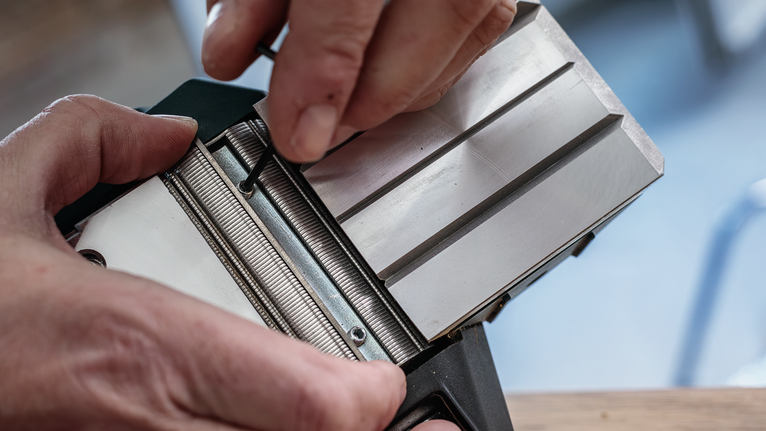 Una persona regola un componente di uno strumento metallico utilizzando una chiave esagonale.