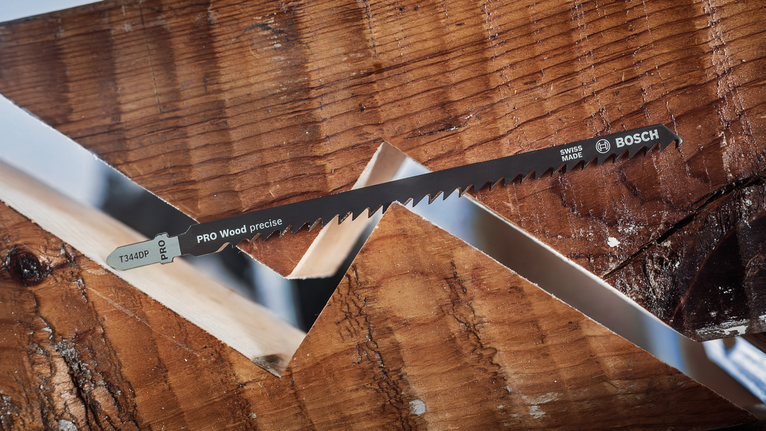 Lama della sega posizionata tra due pezzi di legno ad incastro con tagli angolati.