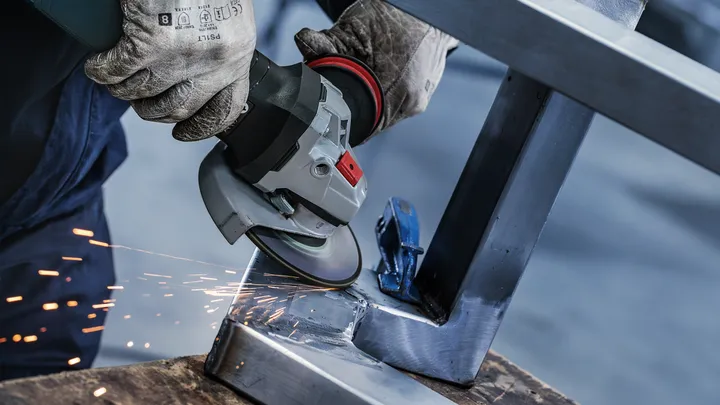 Una persona che indossa un equipaggiamento di sicurezza sfrega contro un telaio metallico, provocando scintille.