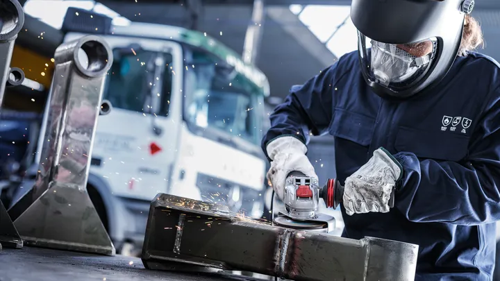 La persona che indossa l'equipaggiamento di sicurezza macina il metallo, creando scintille.