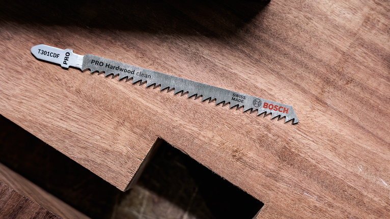 Lama per seghetto alternativo per legno duro appoggiata su una superficie di legno.