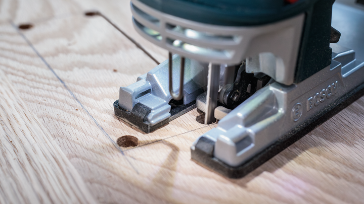 Taglio con il seghetto alternativo di una forma rettangolare su una tavola di legno.