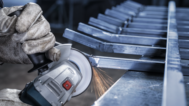 La persona che indossa l'equipaggiamento di sicurezza macina il metallo, producendo scintille.