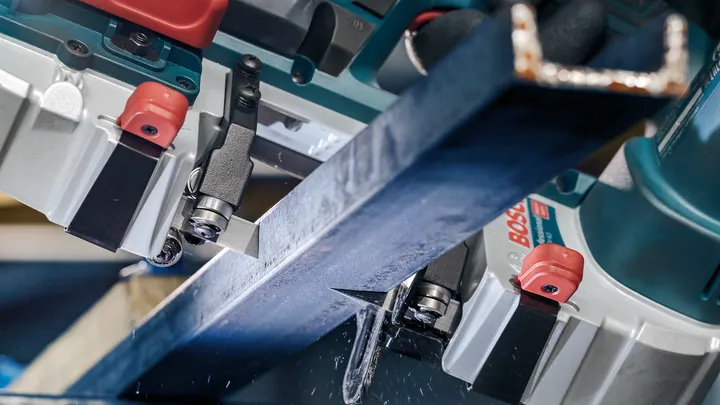 Trave metallica tagliata con precisione da una sega elettrica in un ambiente industriale.