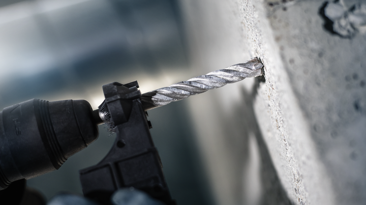 Trapano a percussione che pratica un foro in un muro di cemento.