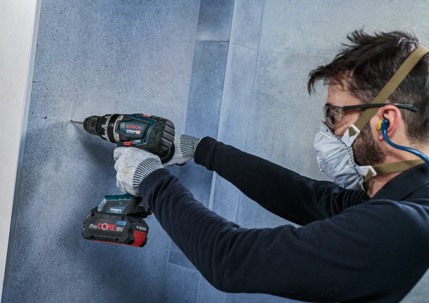 Una persona che indossa un equipaggiamento di sicurezza fora un muro piastrellato.