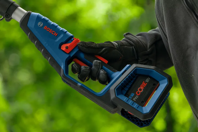 Una persona con indosso dispositivi di protezione individuale tiene in mano una sega a batteria all'aperto.