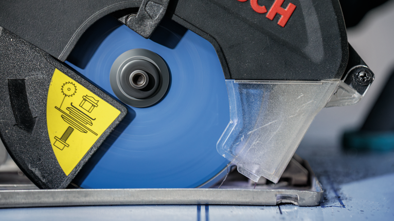 Una sega circolare con lama blu taglia un pezzo di materiale contrassegnato.