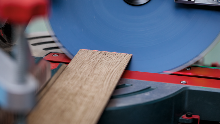 Sega circolare che taglia un'asse di legno su una postazione di lavoro con sega troncatrice.