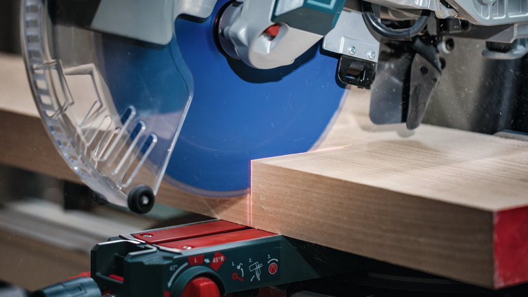 Sega circolare che taglia una spessa tavola di legno in un'officina.