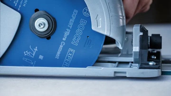 Persona che utilizza una sega circolare con lama blu su una superficie piana.