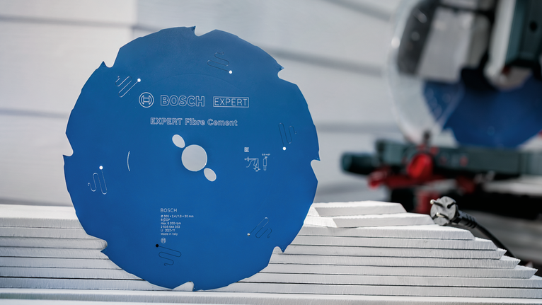 Lama di sega circolare blu posizionata su pannelli di fibrocemento impilati in un'officina.