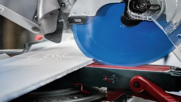 Sega circolare che taglia una tavola di legno su un supporto per sega troncatrice rossa.