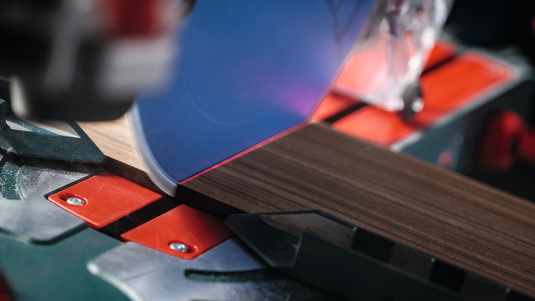 Una sega circolare esegue un taglio preciso su un pezzo di legno scuro.