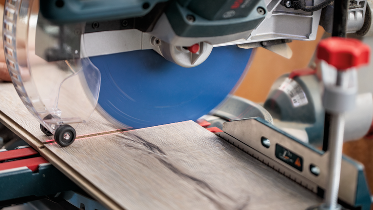 Sega circolare che taglia un'asse di legno su una postazione di lavoro con sega troncatrice.