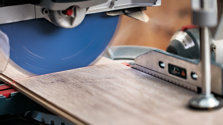 Una sega circolare taglia un'asse di legno lungo una linea rossa.