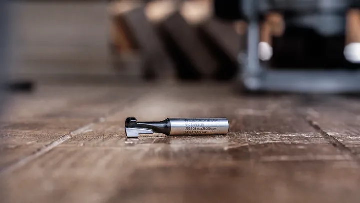 Fresa posizionata su un pavimento in legno in un'officina.