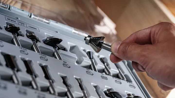 La persona seleziona una fresa da un kit di utensili organizzato.