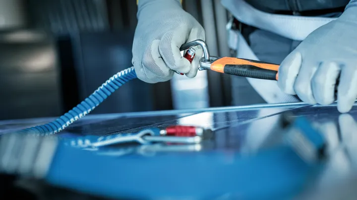 La persona che indossa l'attrezzatura di sicurezza aggancia un moschettone a un'imbracatura di sicurezza.