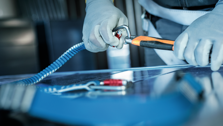 La persona che indossa l'attrezzatura di sicurezza aggancia un moschettone a un'imbracatura di sicurezza.