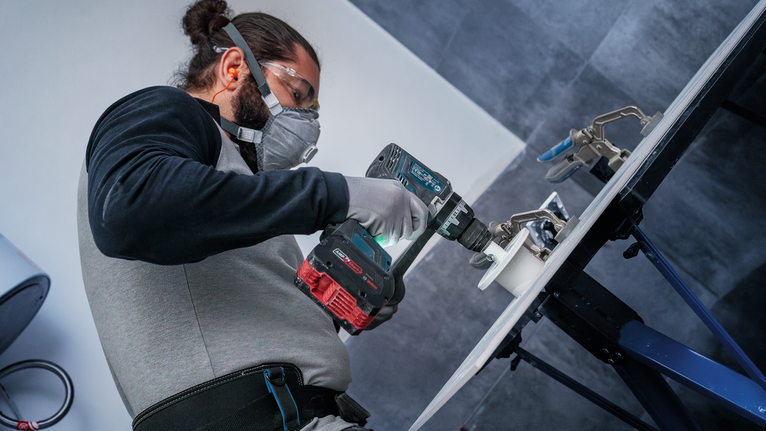 Una persona che indossa un equipaggiamento di sicurezza fora una superficie montata.