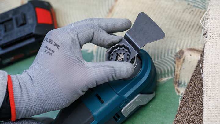 Una persona che indossa un equipaggiamento di sicurezza fissa una lama a un utensile elettrico.