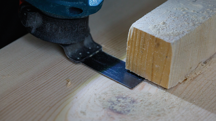 Utensile multiuso oscillante che taglia un pezzo di legno.