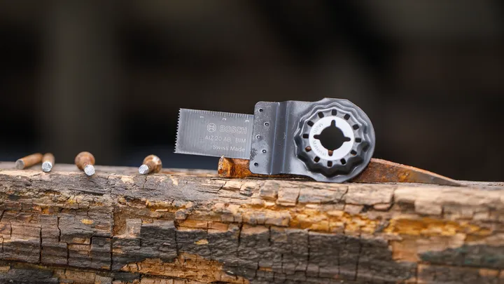 Lama della sega oscillante fissata con chiodi su una trave di legno stagionata.